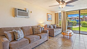 A living room with a beige sofa, a smaller sofa, a glass coffee table, and a ceiling fan. - Tropical 2-BR Condo + Pool +  Hot Tub! 
CHECK OUT OUR SPRING 2026 SPECIALS (Kihei)