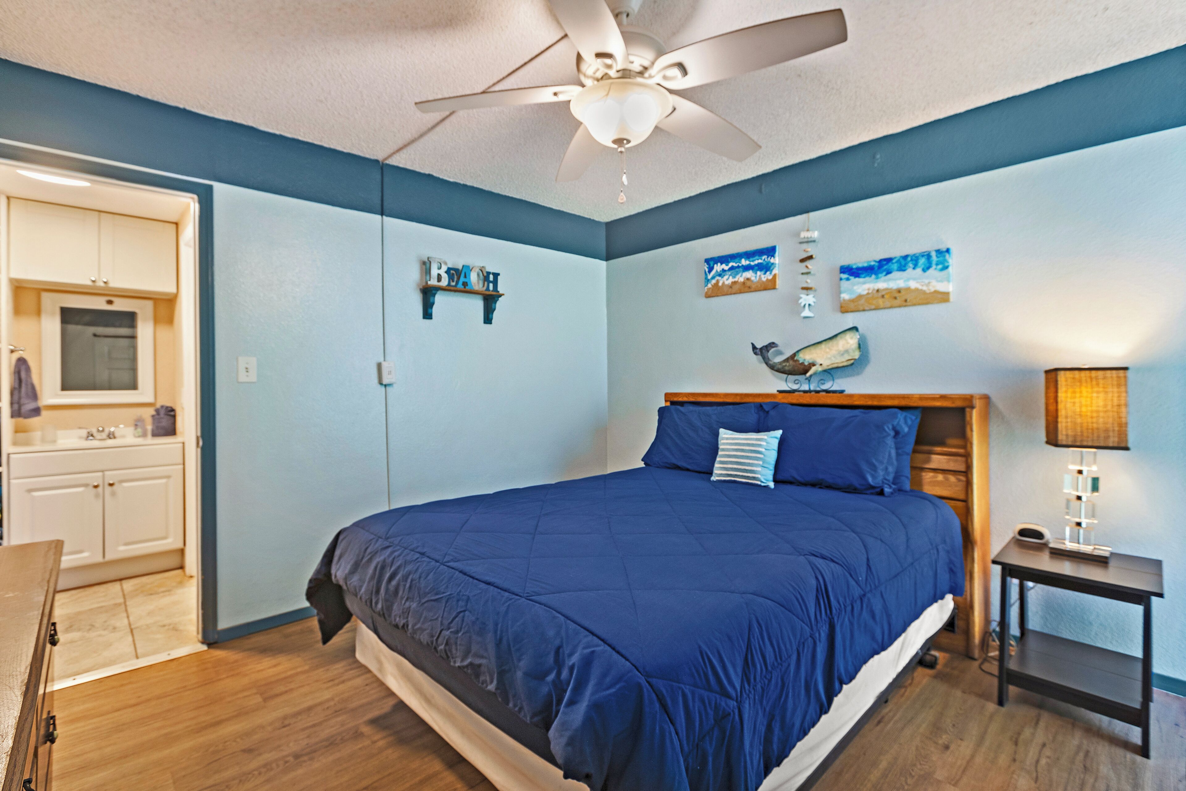 A bedroom with a bed, a ceiling fan, a nightstand, and a wall-mounted shelf.