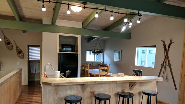 Una cocina con una isla de madera, taburetes de bar y un comedor con sillas.