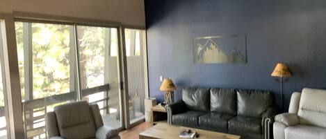 Ein Wohnzimmer mit einer Couch, Sesseln, einem Couchtisch und zwei Lampen.