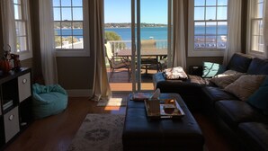 Ein Wohnzimmer mit Meerblick, einer Couch, einem Couchtisch und einem türkisfarbenen Sitzsack.
