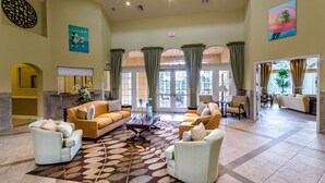A spacious lobby with a large sofa, armchairs, and a patterned rug. There are large windows with curtains, a reception desk, and a painting on the wall. - Stunning Luxury 6 bed 5.5bath  Pool Villa Nr Disney Golf Games Room gated resort (Davenport)