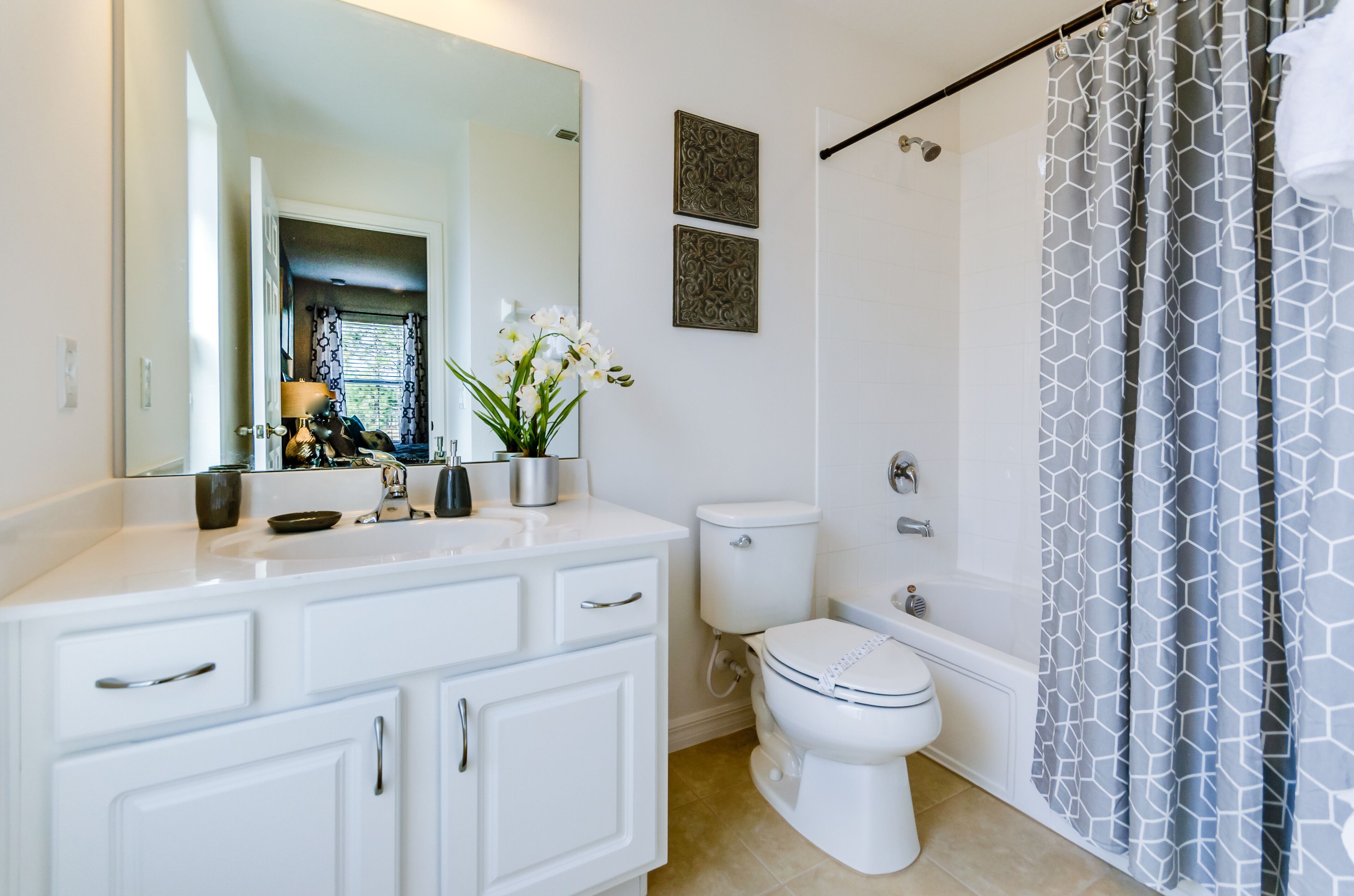 Un baño moderno con un tocador blanco, un inodoro, una bañera y una cortina de ducha.