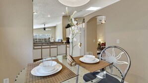 A dining area with a glass table, two chairs, and a vase of white flowers. - Minutes from Disney - Beautiful 3/2 Pool Villa with WiFi in Hampton Lakes  (Davenport)