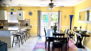A dining area with a table and chairs, a ceiling fan, and a view of the outdoors.