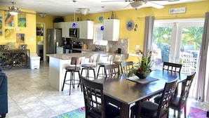 A modern kitchen with white cabinets, a central island, and a dining area with a table and chairs.