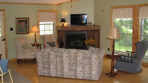 Una sala de estar con chimenea, televisor y ventilador de techo.