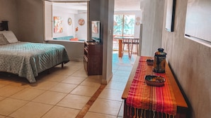 A bedroom with a bed, a desk, and a dining area with chairs.
