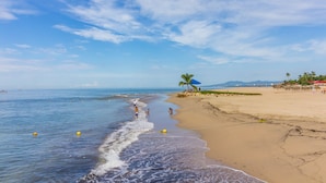 A beach with a clear sky, calm sea, and a few people.