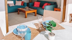 A living room with a sofa, coffee table, and a dining area with a table set for two.