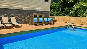 A swimming pool with lounge chairs and a wooden deck.
