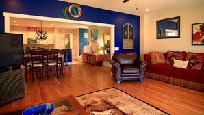 A living room with a red sofa, a brown leather chair, and a dining area with wooden chairs and a table.
