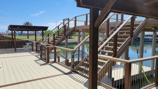 Una terraza de madera con piscina, escaleras y un área de estar cubierta.