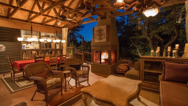 An outdoor patio with wooden furniture, a fireplace, and a dining area with a red tablecloth. - Dancing Bear Lodge, Pine AZ; Luxury Cabin with Views, Spa & Outdoor living area (Pine)