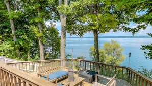 A wooden deck with outdoor furniture, overlooking a calm lake.
