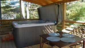 A hot tub on a wooden deck with a table and chairs.