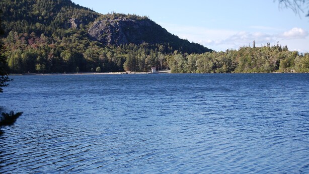 A calm lake with a forested hill in the background.