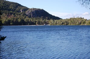 Un lago tranquilo con una colina boscosa al fondo.