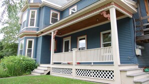 A two-story house with a porch, a chimney, and a small garden.