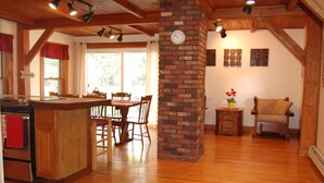 A spacious kitchen with wooden cabinets, a dining area with a table and chairs, a brick fireplace, and a cozy seating area with a chair and a small table.