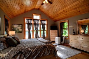 Cozy bedroom with a large bed, two windows, and a dresser with mirror.