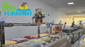 Zona de bufé con diversas opciones de comida, logotipo de 'DDS TURISMO' y una persona sirviendo comida al fondo.