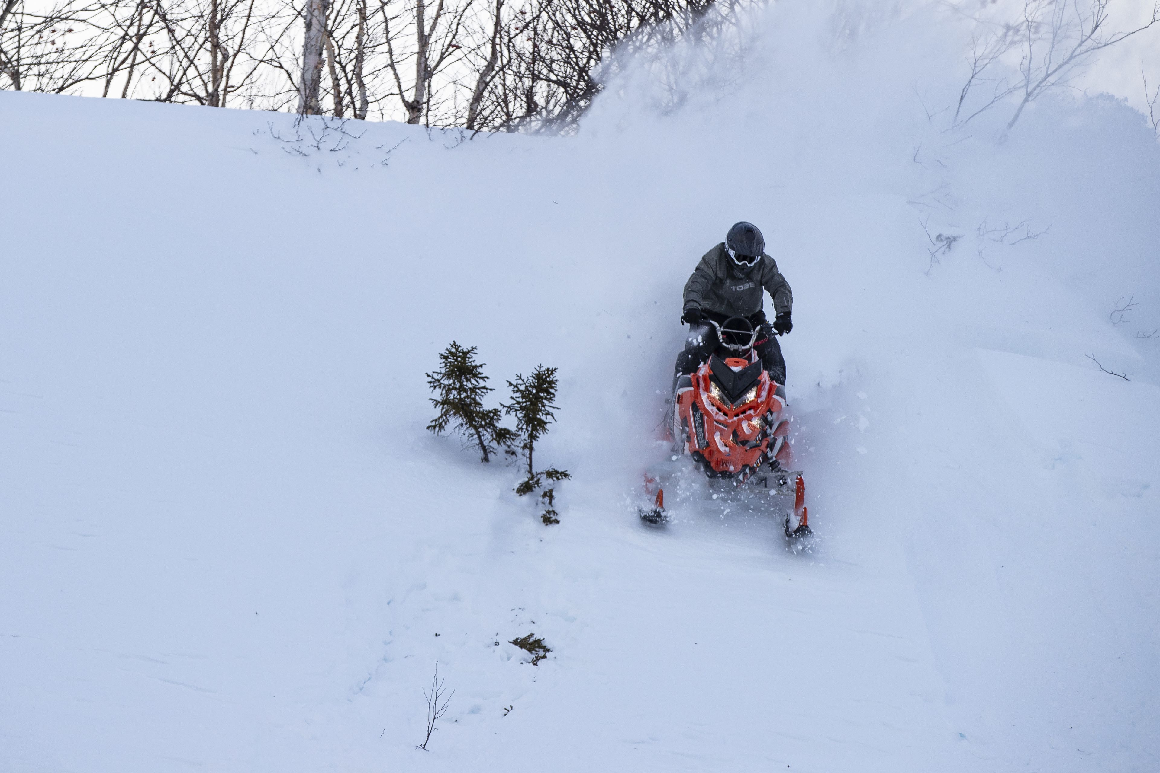 A person riding a snowmobile on a snowy slope.