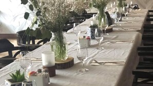 A long dining table set with white tablecloths, glassware, and decorative vases with flowers. - Hôtel Roquemont (Saint-Raymond)