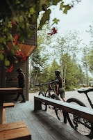 Um deck de madeira com bancos, uma bicicleta e uma pessoa caminhando.