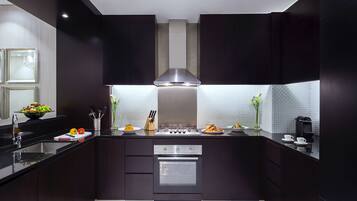 A modern kitchen with dark cabinetry, a stainless steel stove, and a tiled backsplash.
