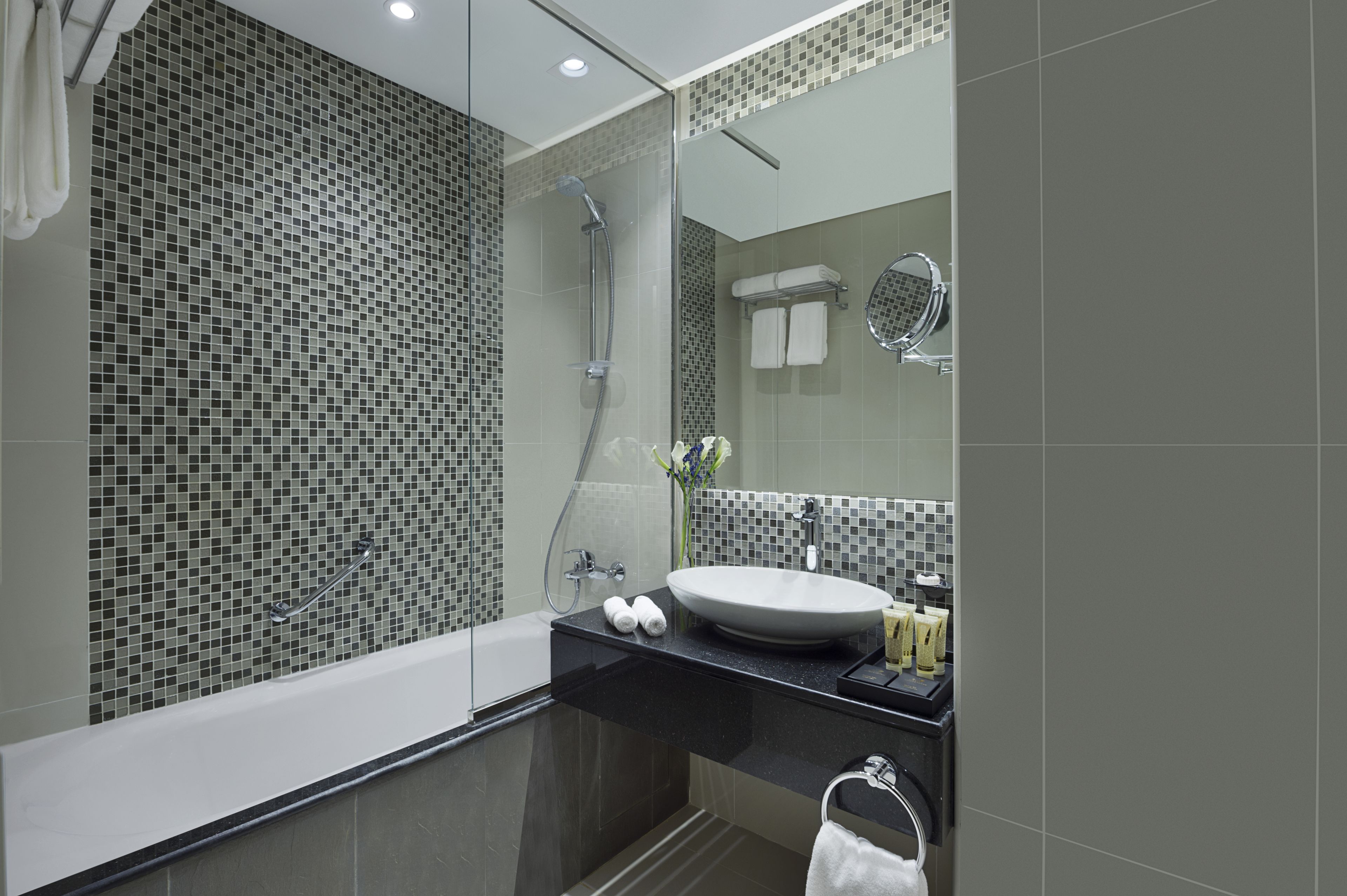 A modern bathroom with a glass-enclosed shower, a white sink, and a large mirror.