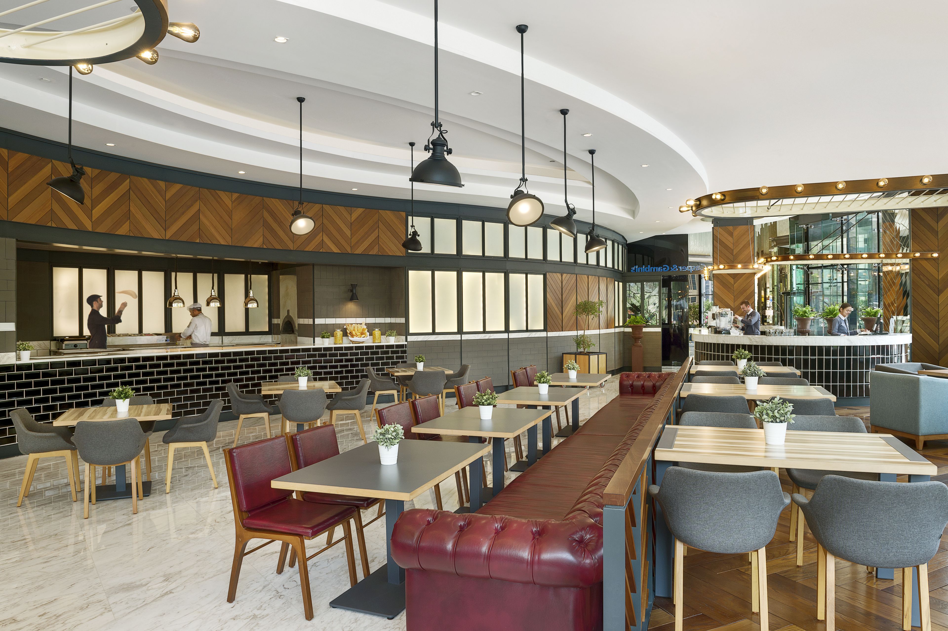 Um restaurante moderno com um balcão extenso, várias áreas de estar e luminárias pendentes.
