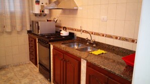 Una cocina con estufa a gas, horno, lavamanos y salpicadero de azulejos.