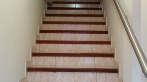 Una escalera con escalones de mármol y barandillas de madera que conduce a una puerta oscura en la parte superior.