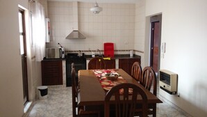 Cocina compacta con mesa, sillas, microondas, estufa y un lavamanos rojo.