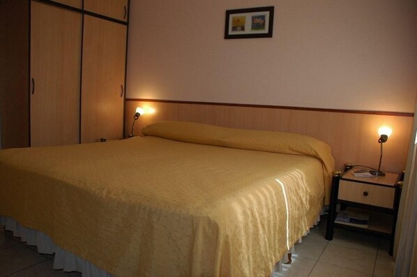 A bedroom with a bed, nightstands, and a wardrobe.