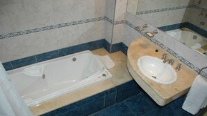 Un baño con bañera, lavamanos y espejo.
