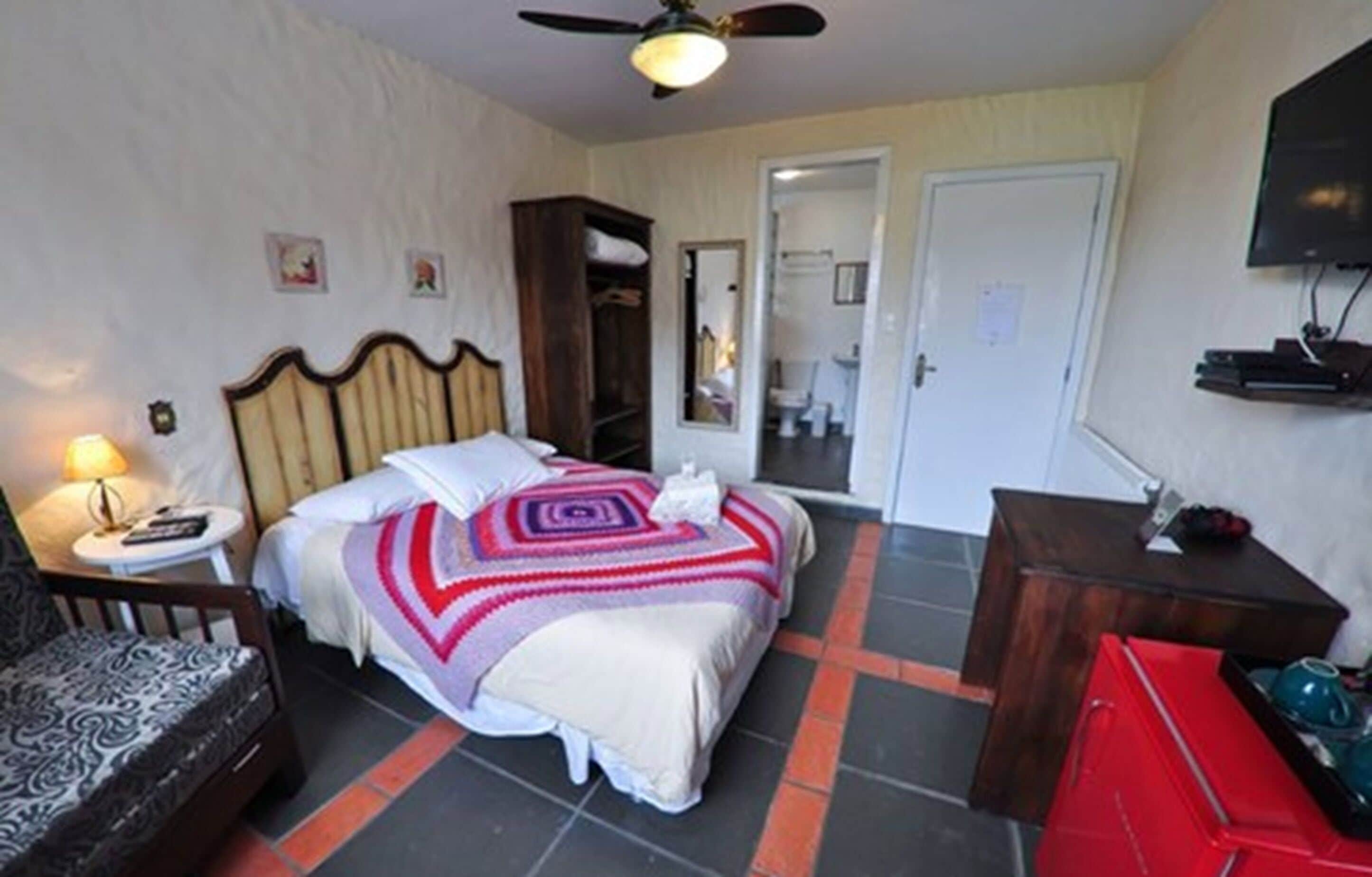 Una habitación de hotel con cama, sillón, escritorio, televisor y armario.