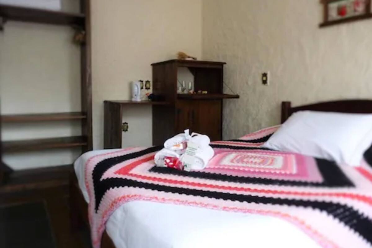 Ein Schlafzimmer mit einem Bett, einem Nachttisch aus Holz und einem an der Wand befestigten Regal.