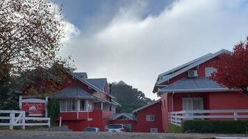 Un bâtiment rouge avec une clôture blanche, une enseigne indiquant « Aardvark Inn », et une voiture garée devant.