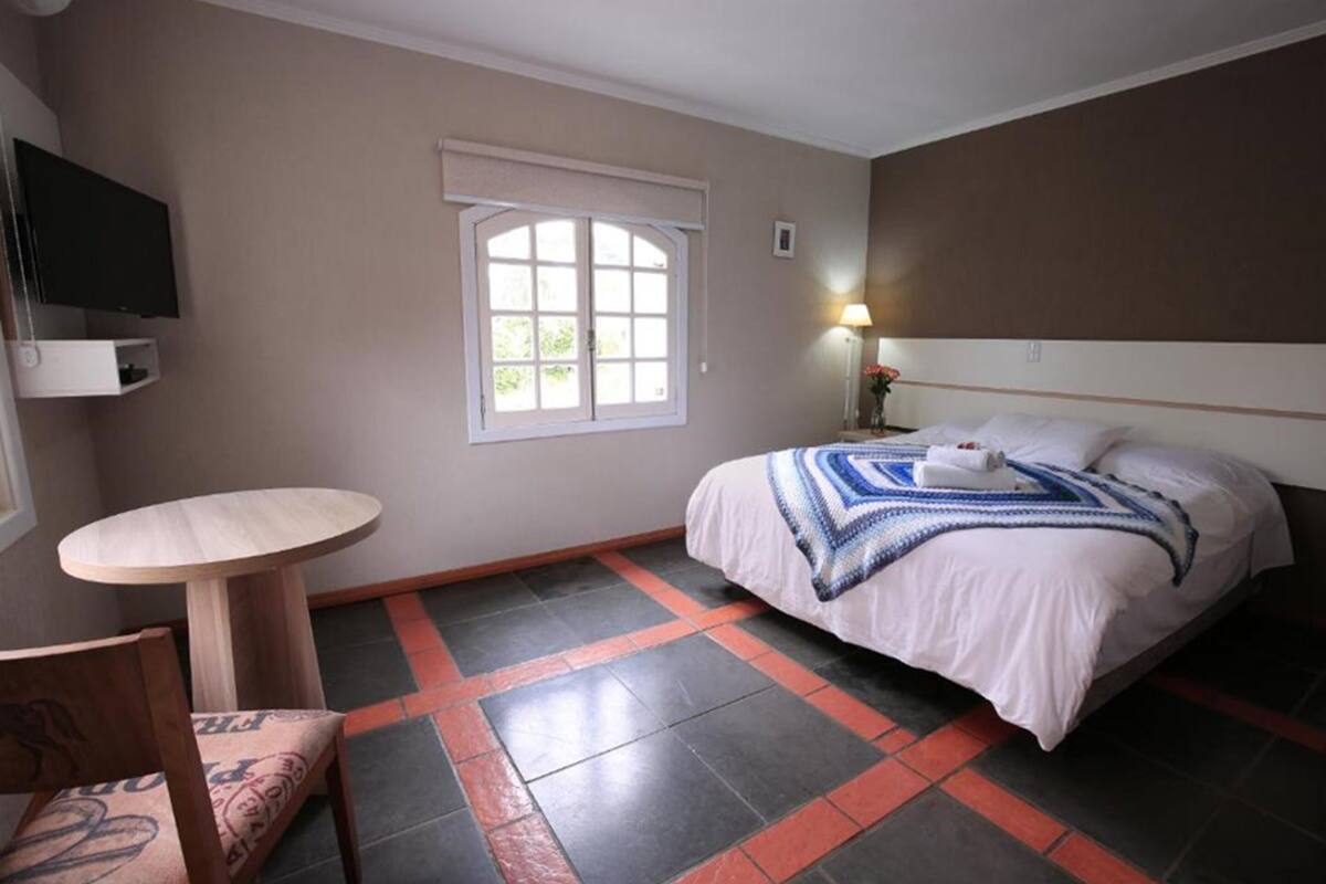 Ein Hotelzimmer mit Bett, Fernseher, kleinem Tisch und Fenster.