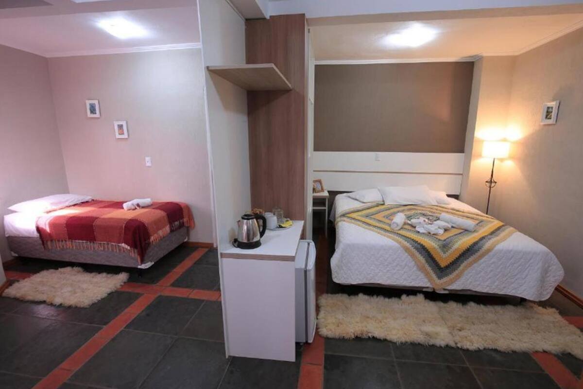 Ein Hotelzimmer mit zwei Betten, einem kleinen Schreibtisch, einer Lampe und einem Teppich.
