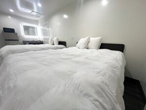 A hotel room with two large beds, a small desk, a mirror, and a window. - Newport Bay Inn (Costa Mesa)