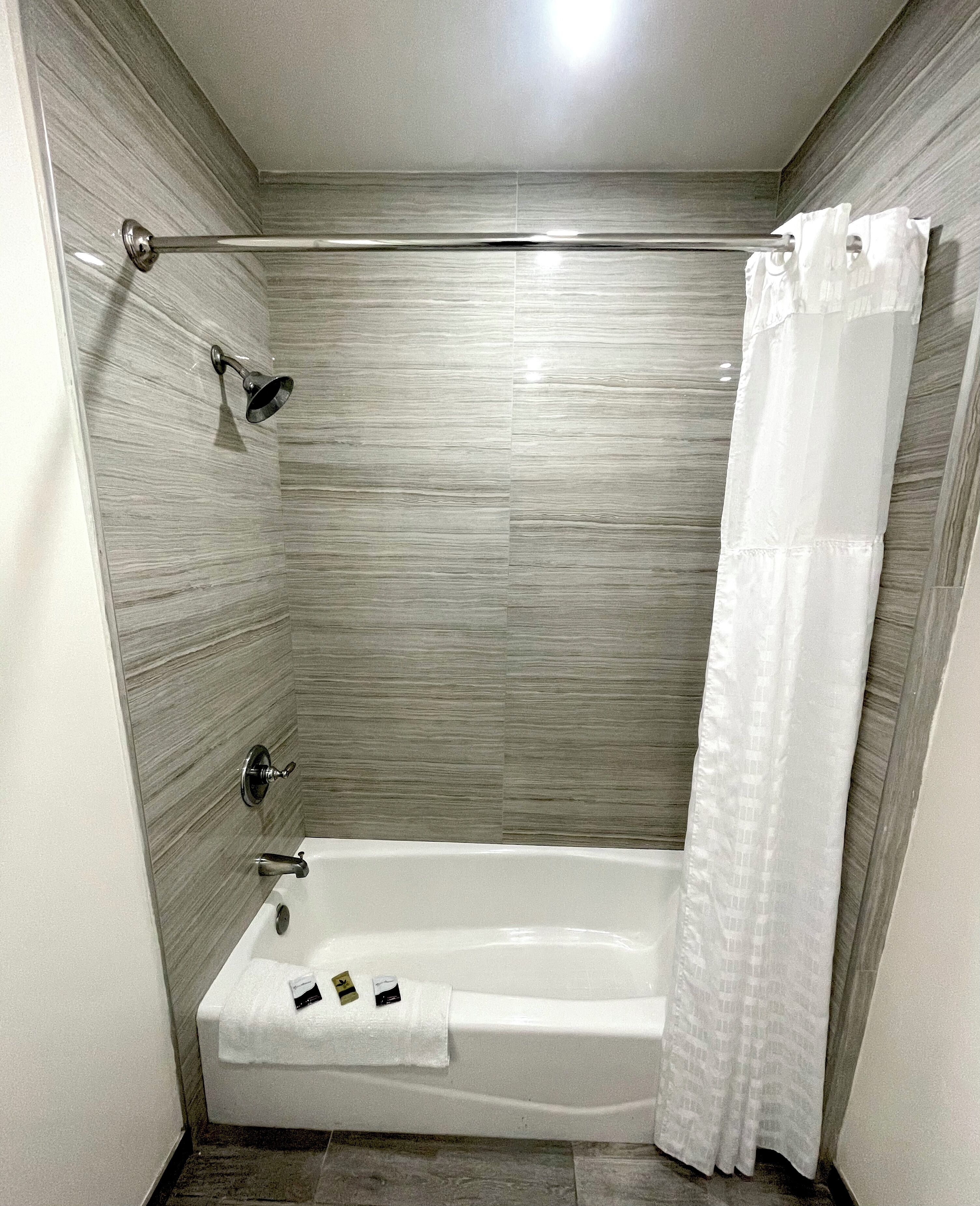 A modern bathroom with a bathtub, shower, and a towel rack.