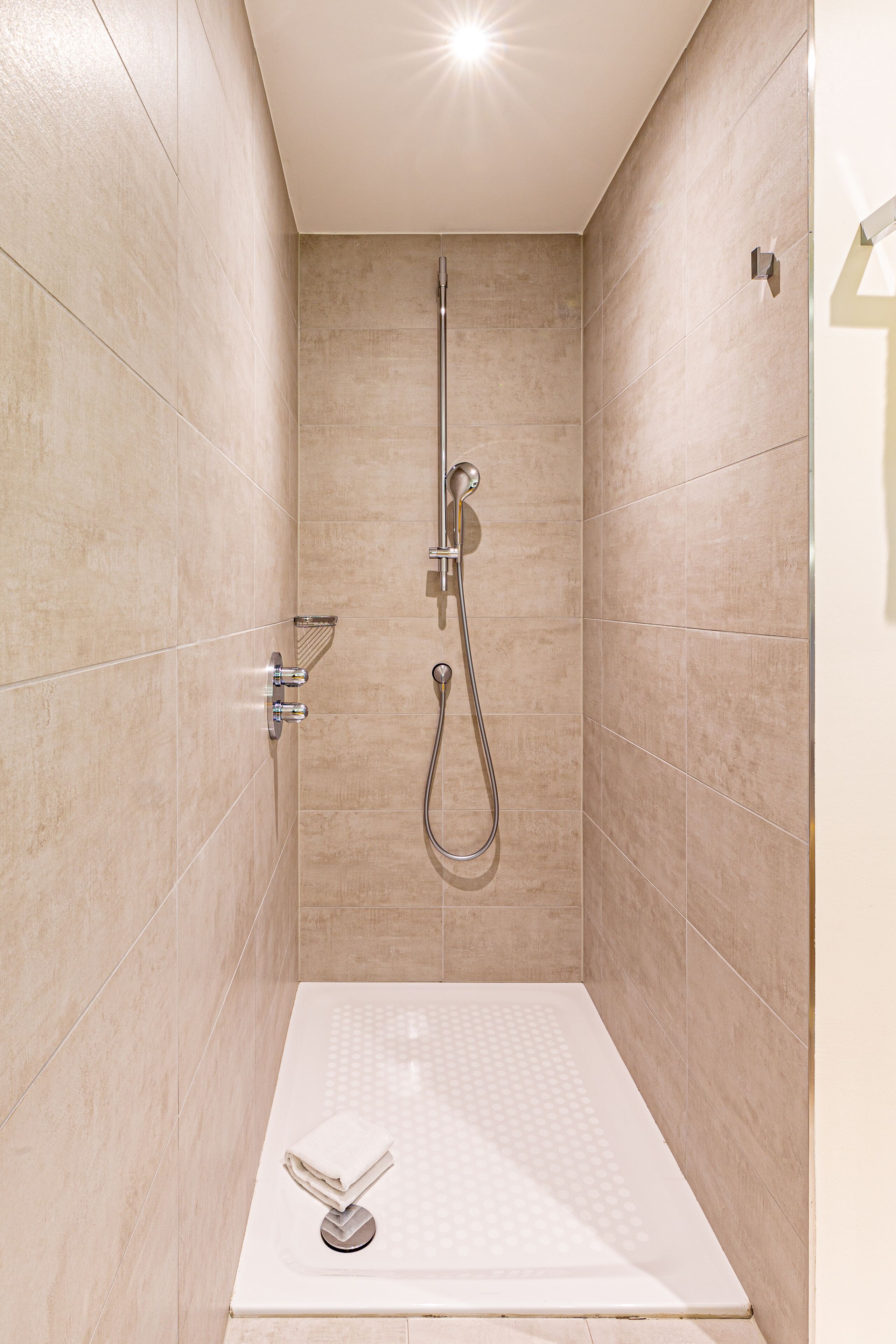 A modern shower with a glass enclosure, a handheld showerhead, and a built-in seat.