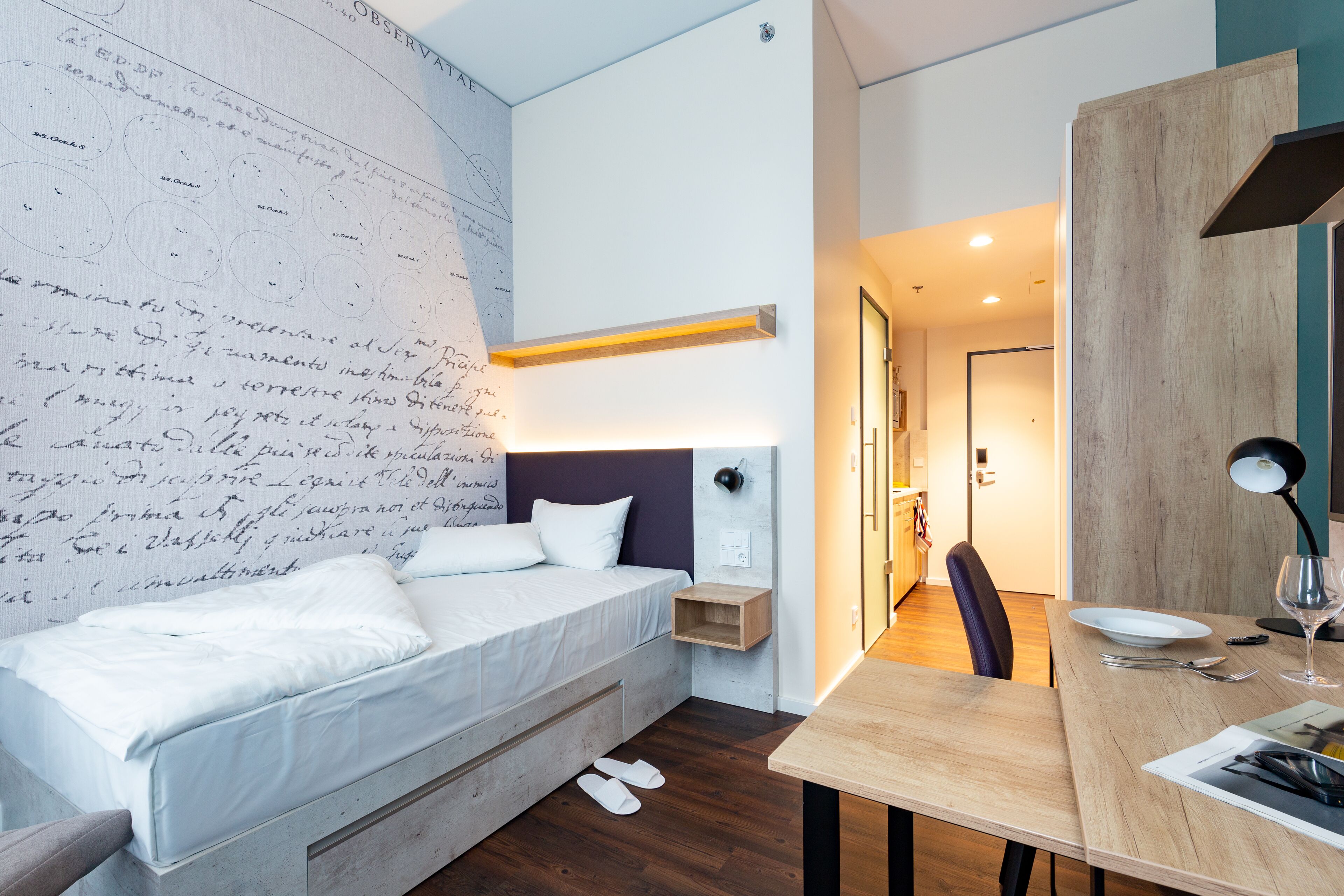Una habitación de hotel moderna con una cama grande, un escritorio con silla, un mapa en la pared y una mesita de noche.