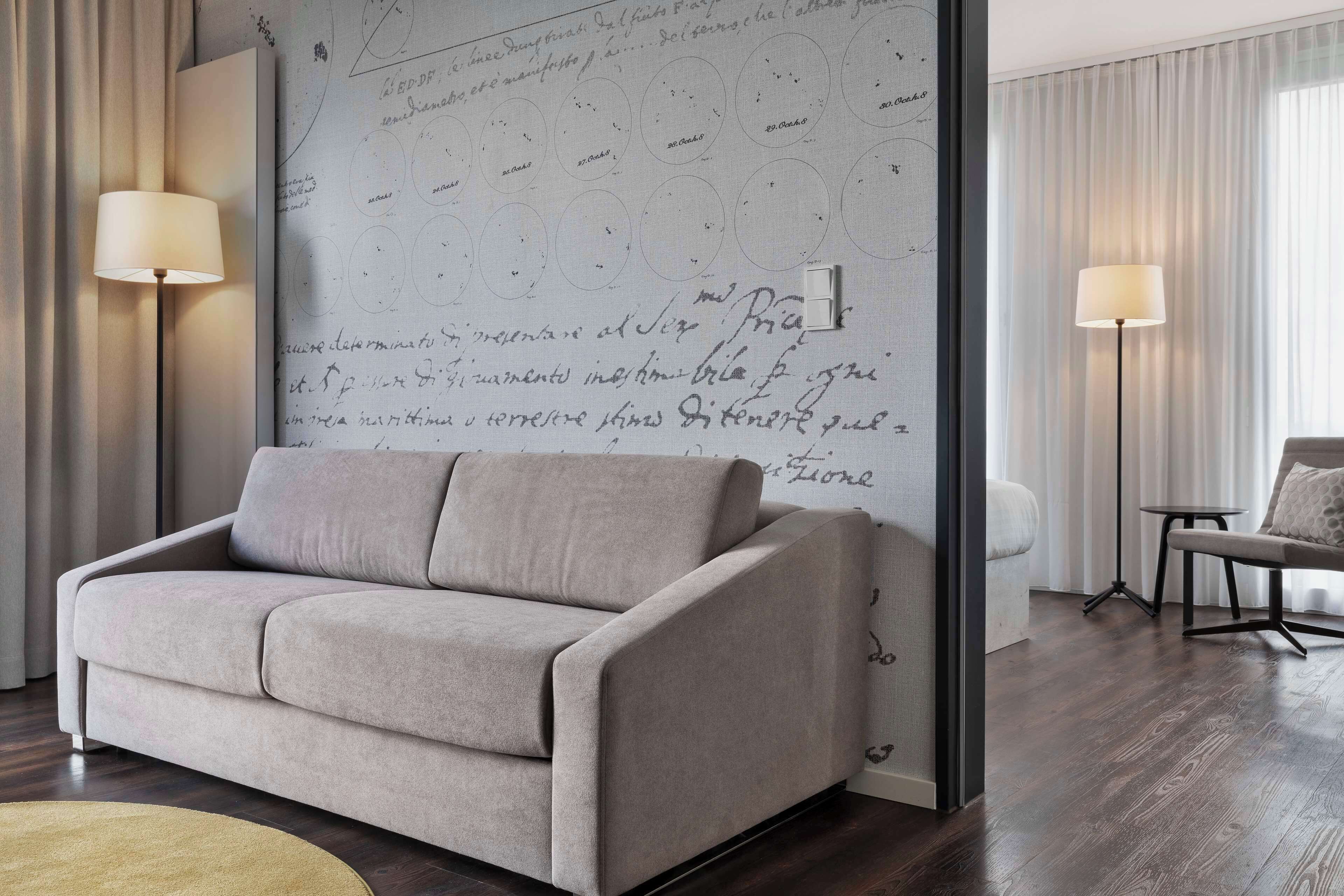 Una sala de estar moderna con un sofá beige, una pared grande con notas escritas a mano y dos lámparas de pie.