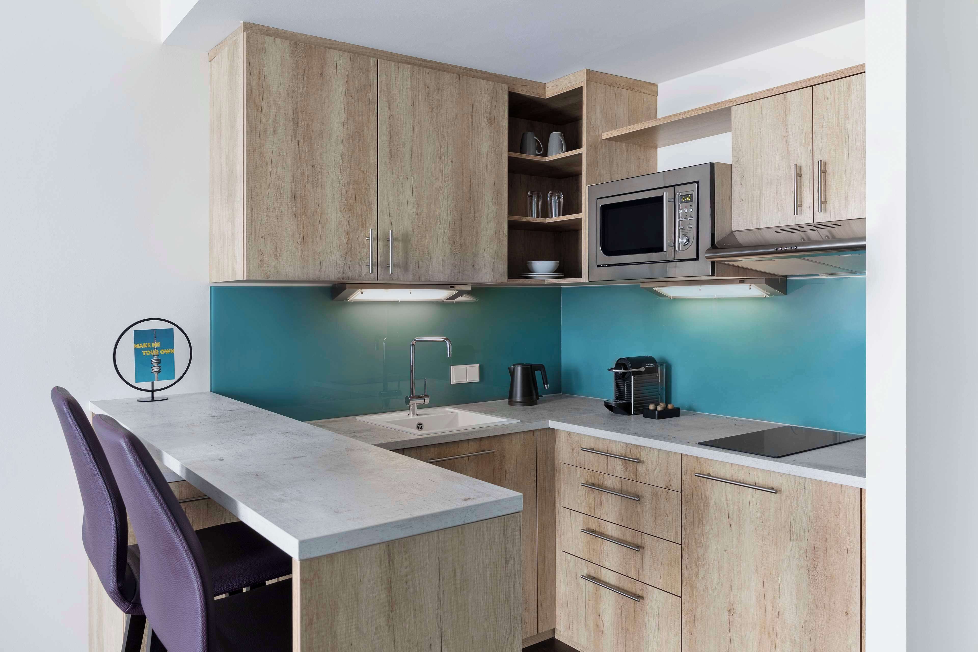 A compact kitchen with wooden cabinets, a microwave, a sink, and a coffee maker.