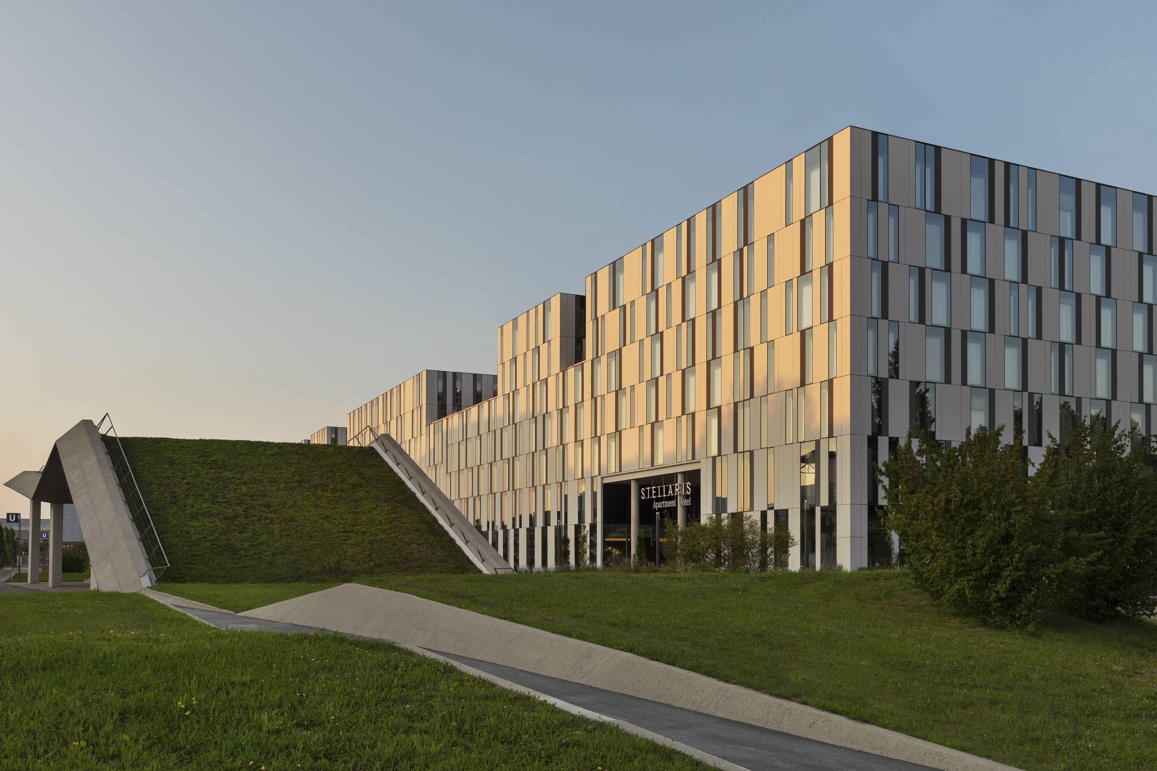 A modern building with a flat roof, a sloped entrance, and a sign reading "Stellar Hotel".