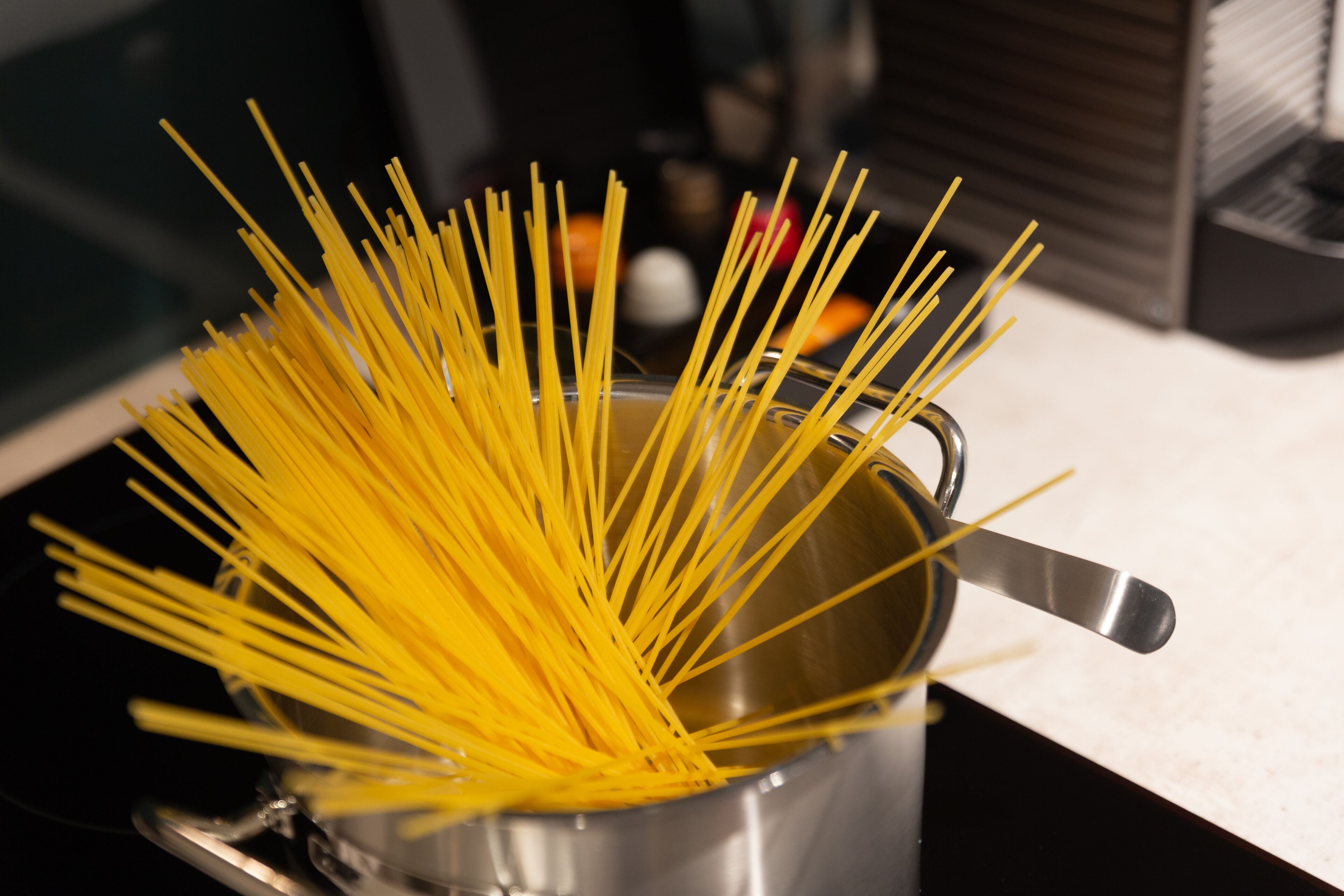 Une casserole de spaghettis crus sur une cuisinière.